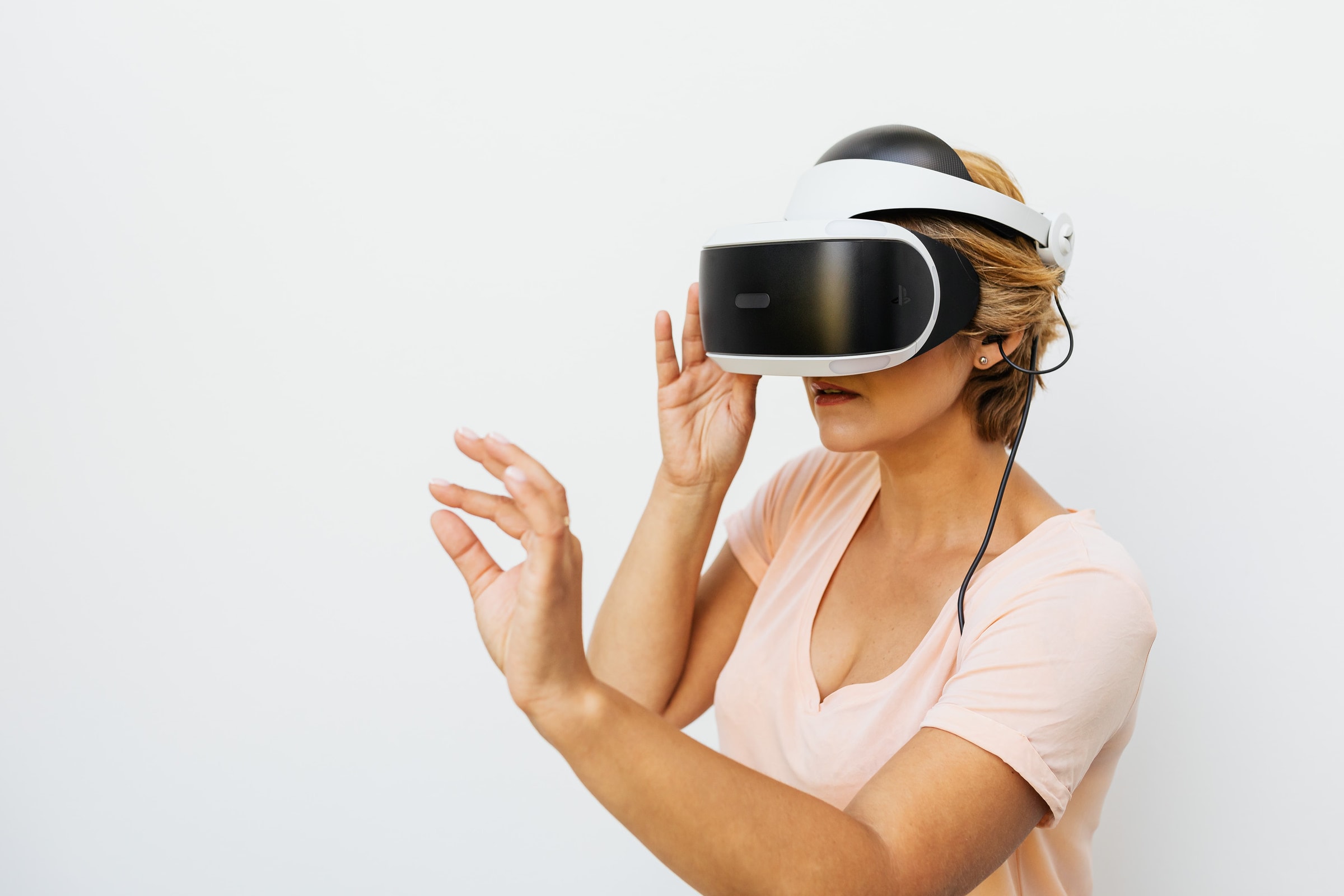 Woman using a VR headset immersed in a virtual reality world, with a white background.