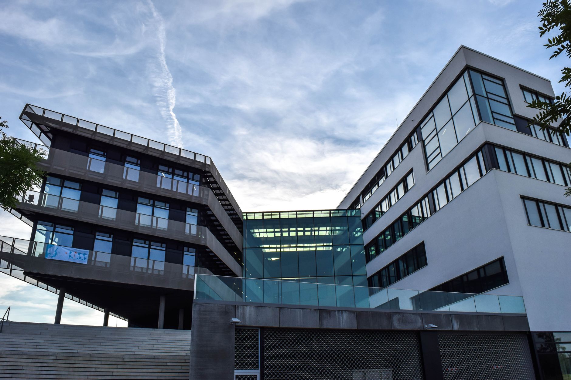 A modern glass-facade building against a blue sky, featuring innovative architecture.